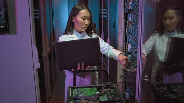 Female IT Specialist Checking Equipment in Data Center