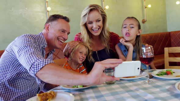 Family taking selfie with mobile phone in restaurant 4k