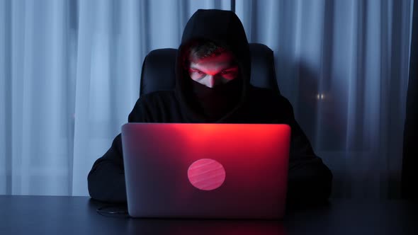 Man hacker face looking at computer screen in dark room. Cyber security concept