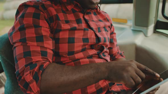 Young African Farmer Using Tablet While Sitting in the Tractor Cabin