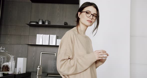 A Beautiful Young Woman is Drinking Tea Cup in the Modern Kitchen Room at Home