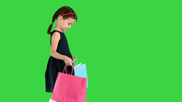 Beautiful Little Girl in Black Dress Walking with Shopping Bags on a Green Screen, Chroma Key