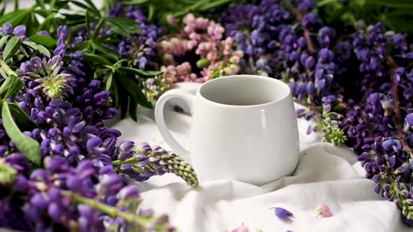 Spring Composition with Flowers and a Cup of Tea on a White Sheet. Flowers and a Cup of Coffee Among