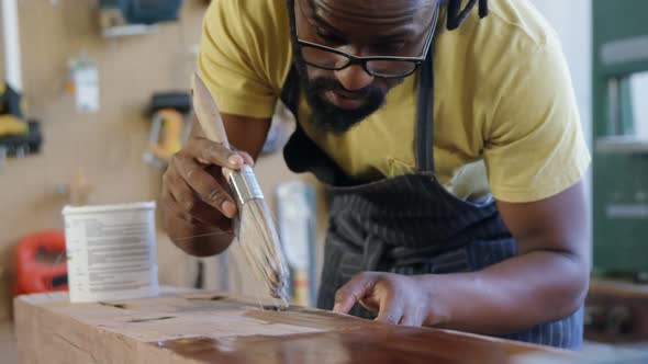 Attentive carpenter painting wooden plank 4k