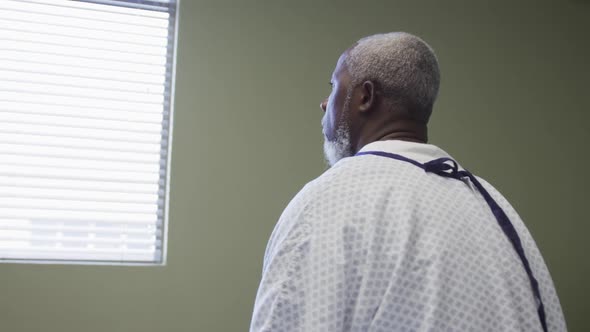 Depressed african american senior male patient looking out of the window at hospital