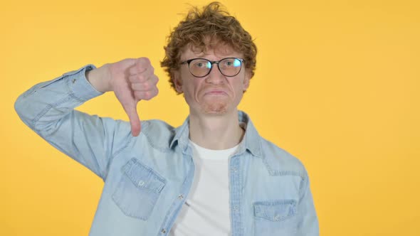 Redhead Young Man with Thumbs Down Yellow Background
