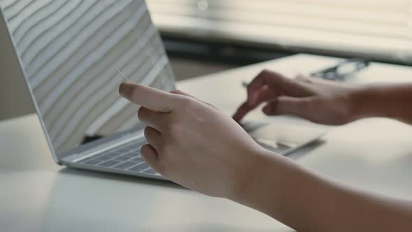 Close up hand young Asian female using a laptop shopping online and use a credit card payment.