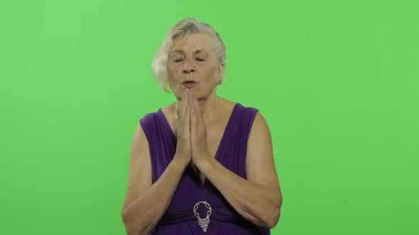 An Elderly Woman Prays with Hands Clasped Together. Old Grandmother. Chroma Key