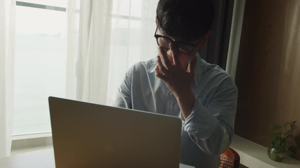 Young Attractive Asian Vietnam Man Busy Work Computer or Smart Tablet on Laptop at Home in Freelance