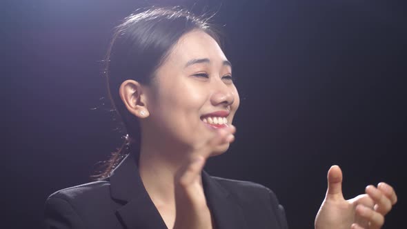 Speaker Woman In Business Suit Clapping Her Hands And Looking Around While Standing In Black Studio