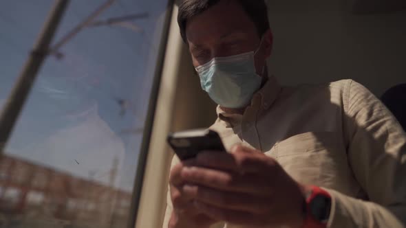 New Norm of Public Transport Person Travels on Train Sits at Safe Distance and Uses Phone Wearing