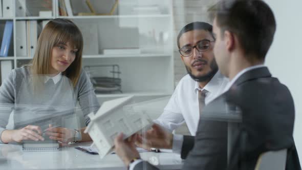 Professional Architects Discussing House Model at Office Meeting