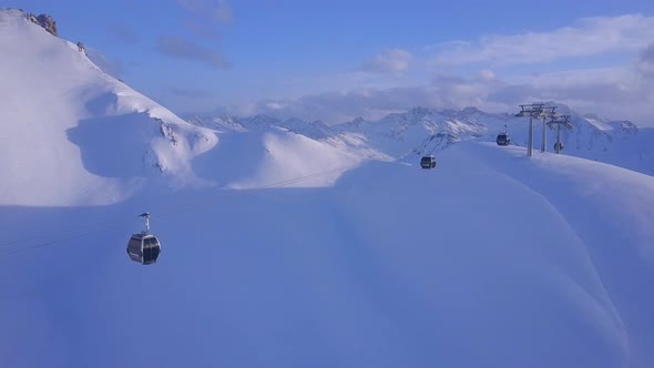 Aerial drone view of a ski gondola lift and mountains at a ski resort.