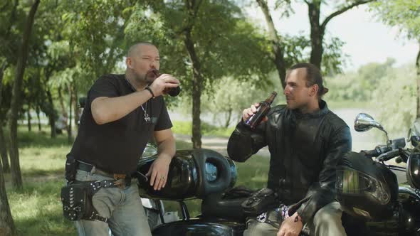 Brutal Bikers Drinking Beer Near Motorbike in Park