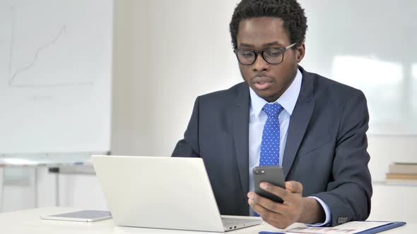 Multitasking African Businessman Using Laptop Tablet and Smartphone