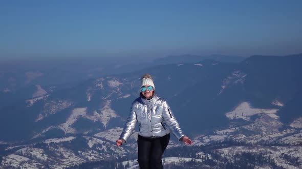 Young Woman Is Jumping at the Top of Mountain with Beautiful View Powerful Snowy Mountains and Blue