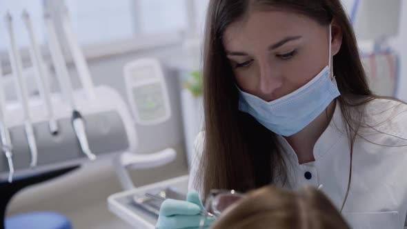 Female Dentist in Gloves Consulting and Using Tools for Working with Patient