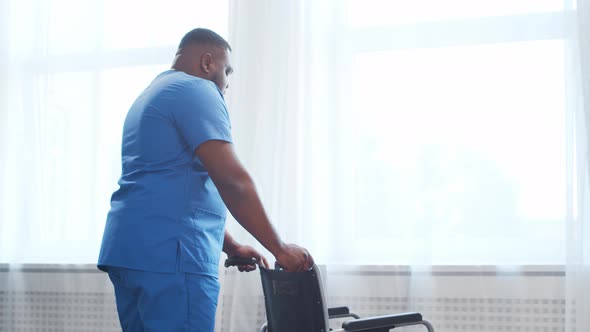 African-American caregiver and old disabled man in a wheelchair. Nurse and handicapped patient.