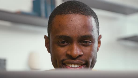 Smiling man receiving news chatting on the internet using laptop