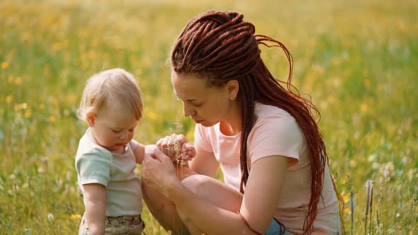 Mom with a child are sitting in a clearing or park. Parenting Maternity Joy Family Concept.