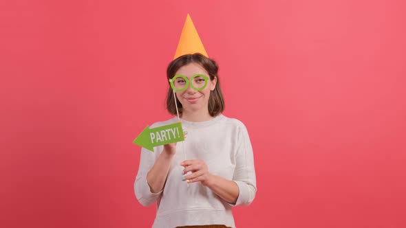 Happy Young Woman in Party Hat Holding Birthday Accessories on Red Background