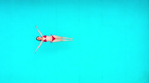 View From the Top As a Woman in a Red Swimsuit Lying on Her Back in the Pool