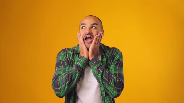 Happily Surprised and Shocked African American Man Against Yellow Background
