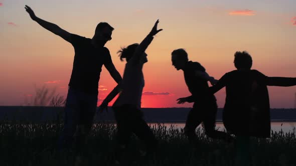 Silhouettes of Young People Have Fun at Sunset