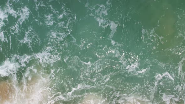 Top View of the sea surface Waves crashing on beach sand