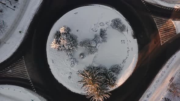 Above snow covered roundabout with no cars, calm urban junction, aerial