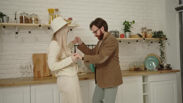 Young Caucasian Husband Dancing with His Beautiful Longhaired Wife in the Kitchen Celebrating Their