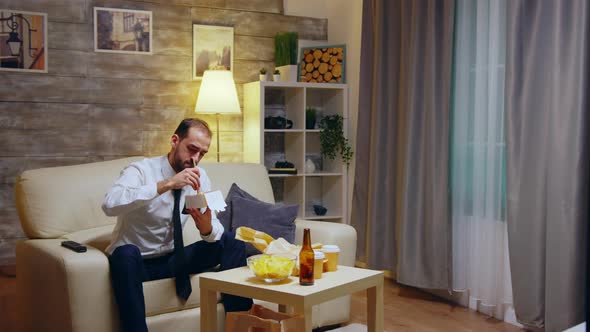 Businessman Sitting on Couch Eating Takeaway Noodles From Box