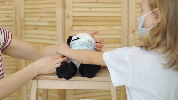 Little Girl Putting Protective Mask on Toy Panda