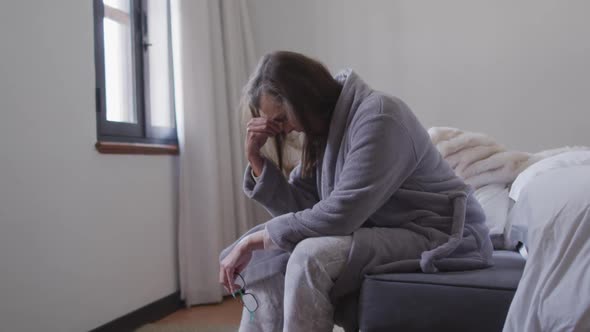 Stressed woman sitting on bed at home