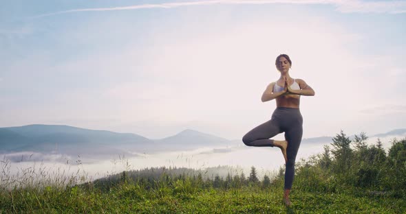 Active Woman Balancing on One Leg and Meditating Outdoors