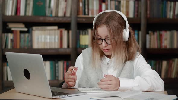 Teen Girl School Wear Headphones Learn Watching Online Webinar Writing on Notebook Webcast Class