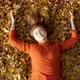 Happy beautiful young woman ying in autumn foliage in park enjoying life - VideoHive Item for Sale