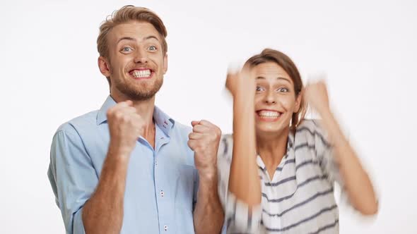 Young Caucasian Couple on White Background Unexpectedly Winning and Actively Rejoicing in Slowmotion