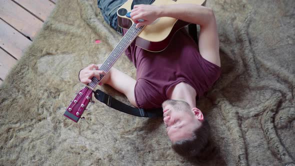 Man with Acoustic Guitar Singing and Playing Guitar in Lying Position