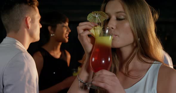 Beautiful young woman having a glass of cocktail in bar