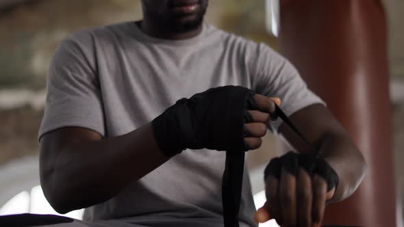 Male Boxer is Wrapping Hands with Black Bandage Close Up