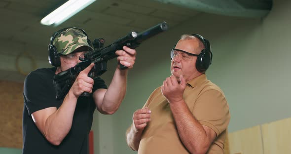 A Man Learns How to Shoot a Rifle at the Shooting Range The Instructor Shows the Trainee the Correct