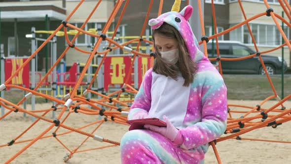 Young Girl in a Protective Mask at the Playground.