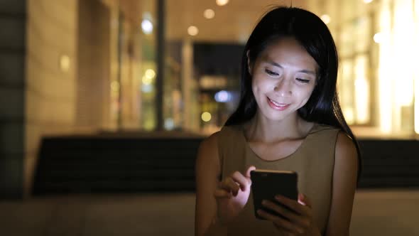 Woman use of smart phone in city at night 