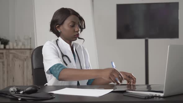 Medicine, People and Healthcare Concept - Happy Female African American Doctor or Nurse Writing