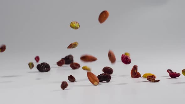 Healthy trail mix falling onto a white surface in slow motion