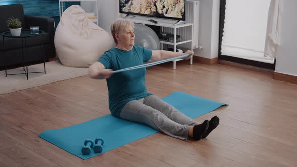 Retired Adult Using Resistance Band to Stretch Arms Muscles