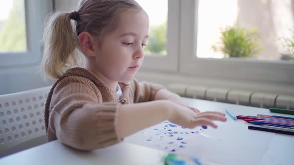 Little girl using gouache for drawing with fingers on paper at home
