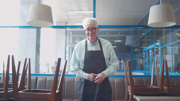 Mature Restaurant Owner Tie Apron and Smile at Camera