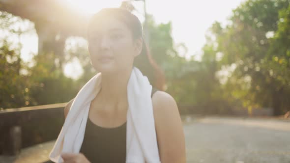 Happy Asian woman running in park on public green background